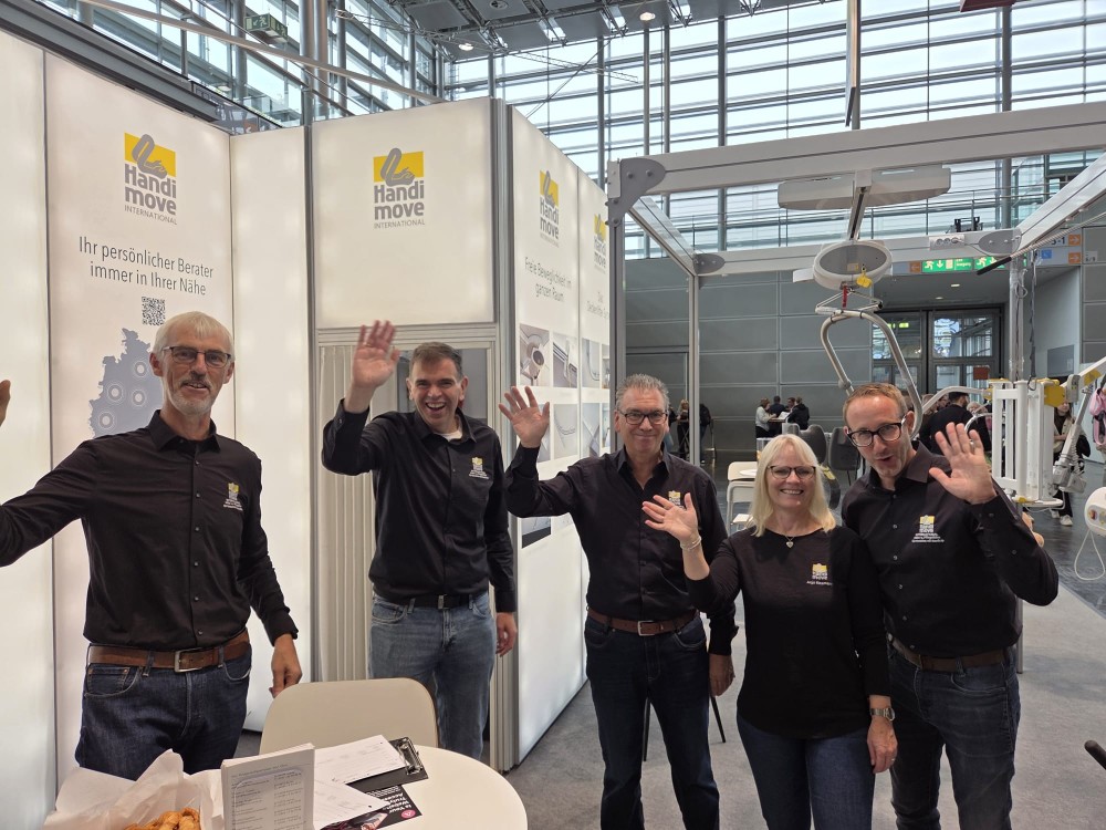 unser Team auf dem Messestand der Rehacare winkt dir
